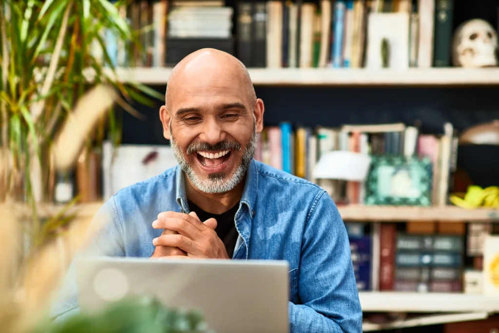 Country-Bank-Man-sits-behind-computer-looking-happily-at-his-bank-accounts