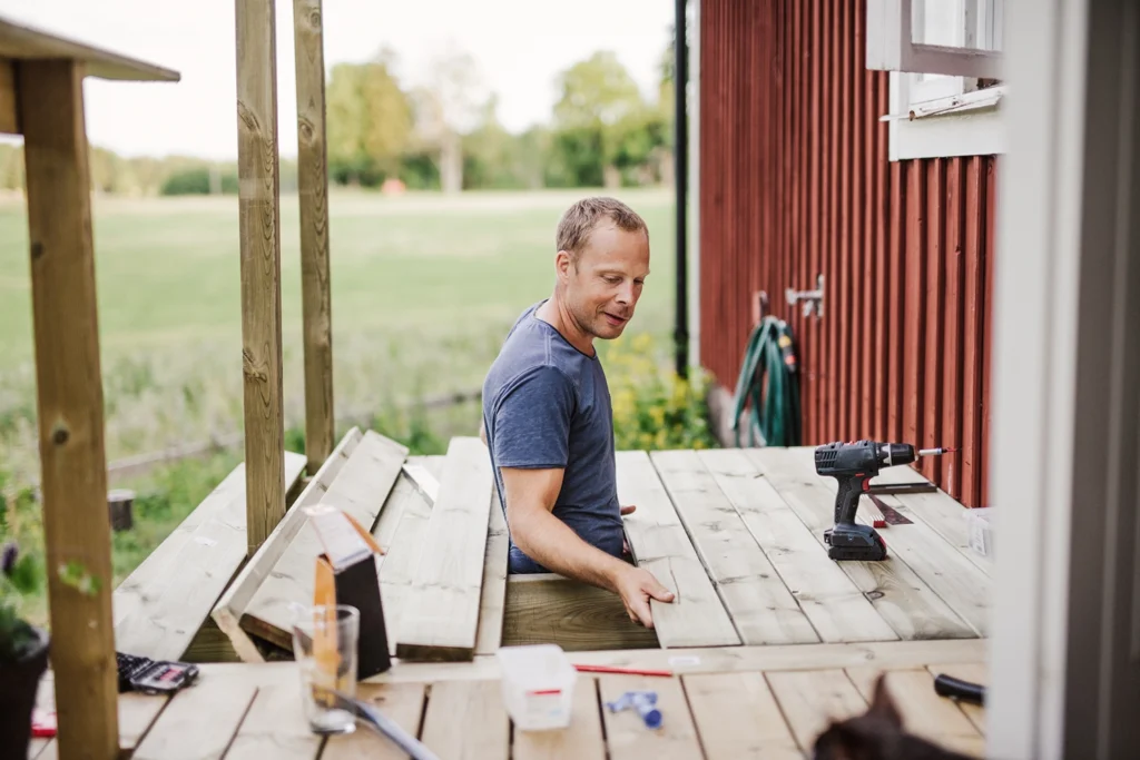 Country-Bank-man-building-a-deck-out-back-of-a-home-structure