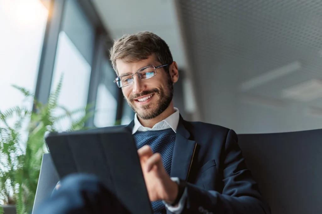 Country-Bank-man-sitting-in-chair-on-tablet-smiling-at-the-ease-of-ordering-business-checks-online