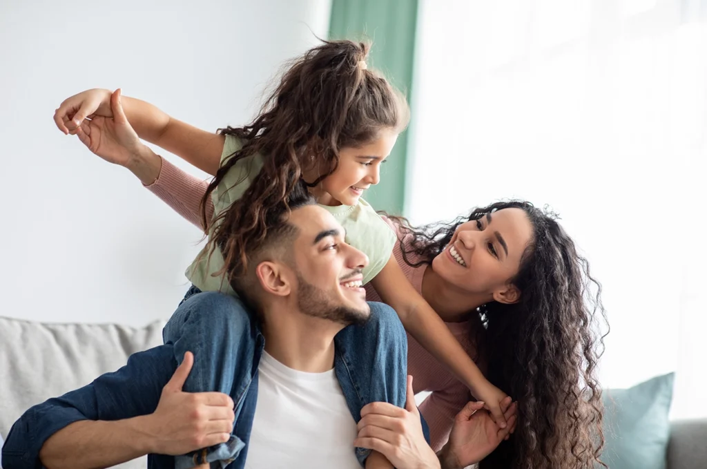 Country-Bank-mother-and-father-hugging-daughter-who-is-sitting-on-his-shoulders
