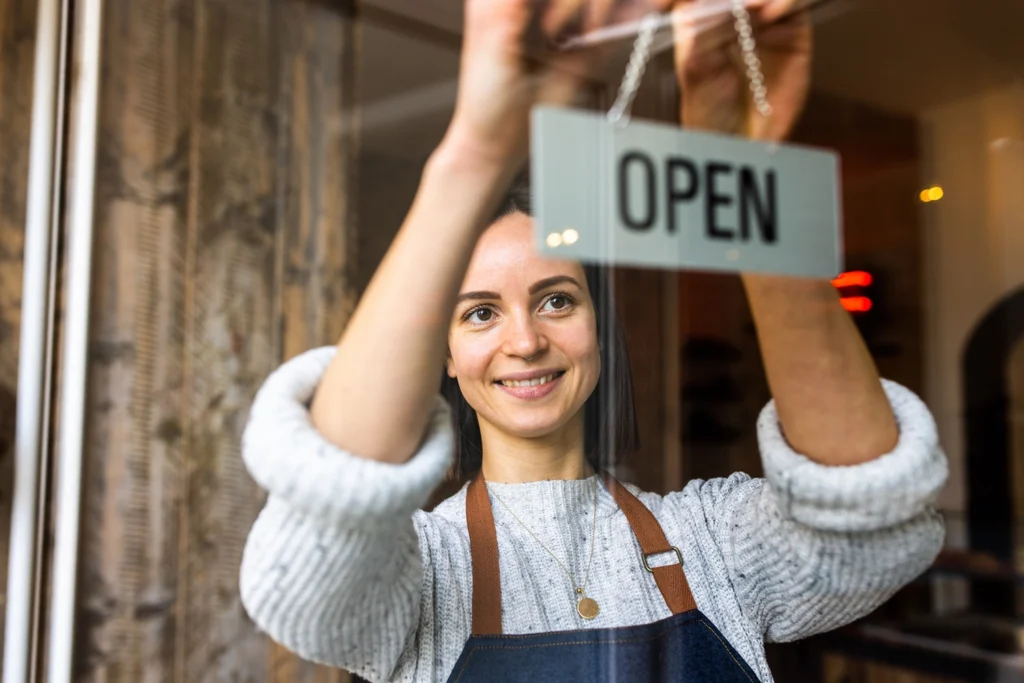 Country-Bank-woman-hangs-open-sign-at-her-business-storefront