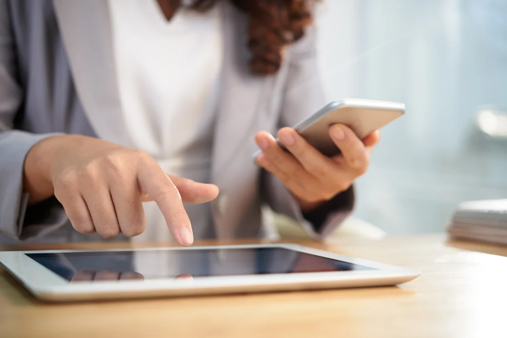Country-Bank-woman-holding-cell-phone-and-typing-into-her-tablet
